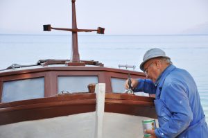 Old man painting boat
