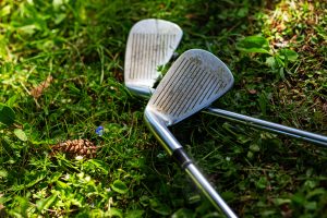 Detail of two golf clubs on grass. Selective focus